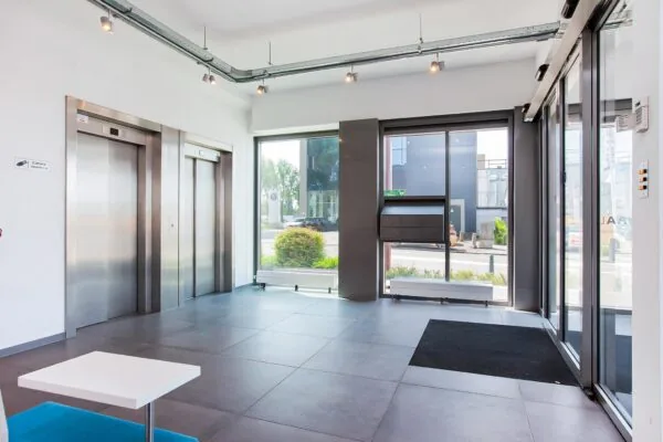 Moderne entreehal met twee liften, grote ramen en postvakken aan de Laan der Verenigde Naties.